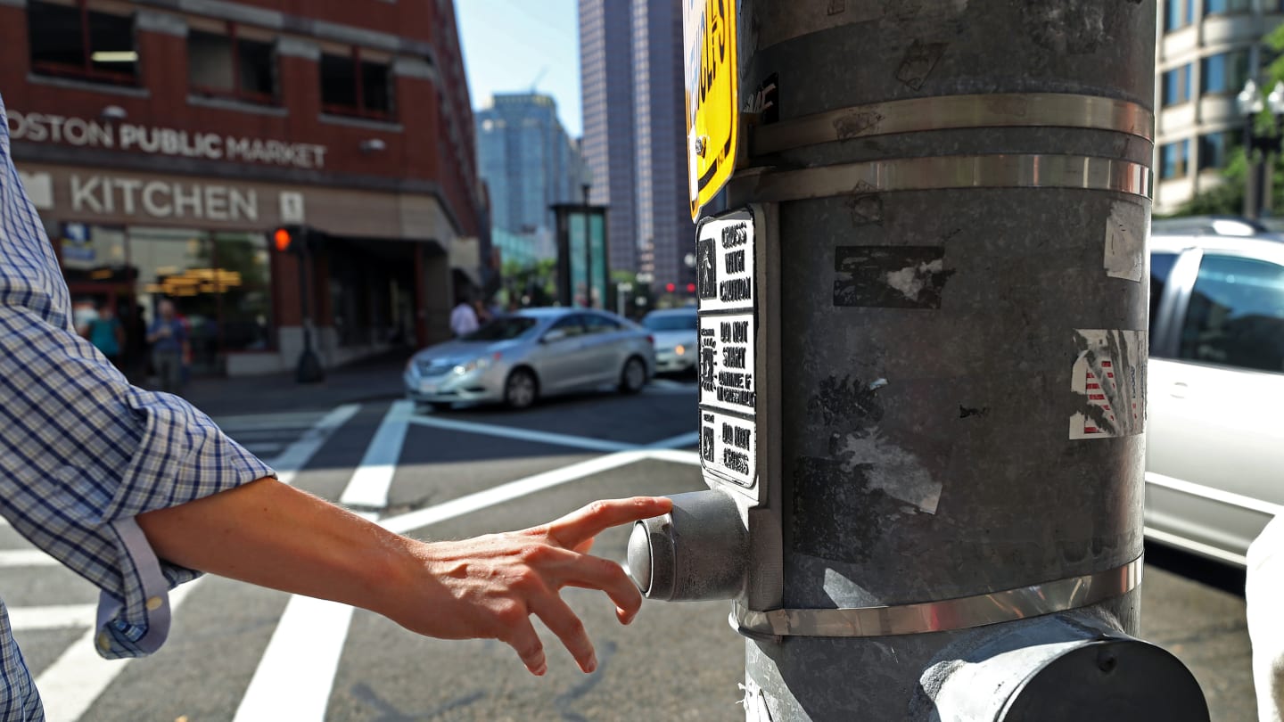 BOSTON, MA - JULY 21: A pedestrian presses a traffic signal button at Congress and Sudbury Streets in Boston on Jul. 21, 2017. The vast majority of these buttons that dot downtown neighborhoods don't actually do anything. Thats by design. Officials say the citys core is just too congested  with cars and pedestrians  to allow any one person to manipulate the cycle. (Photo by David L. Ryan/The Boston Globe via Getty Images)