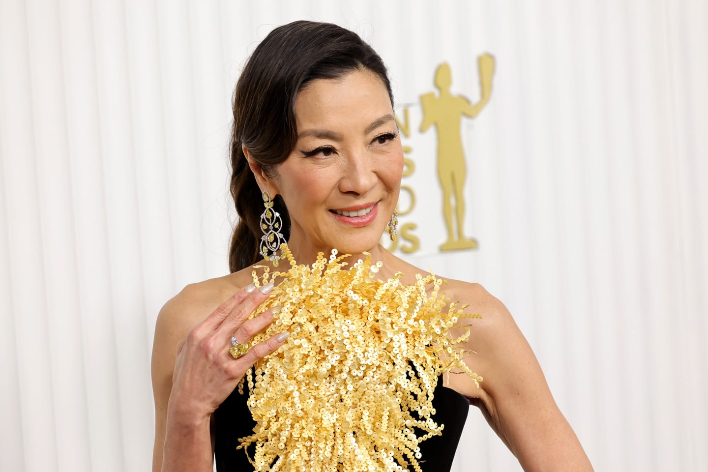 Michelle Yeoh turned heads in a black silk column dress with a fringed gold sequin panel from Schiaparelli's Spring-Summer 2023 Haute Couture collection. She completed the look with Moussaieff jewelry.