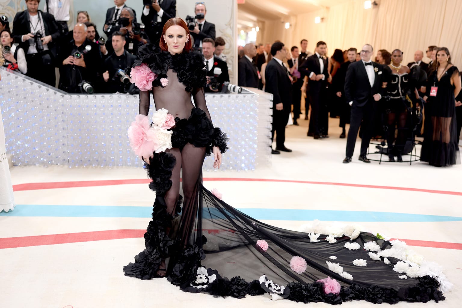 Modelja Karen Elson me një fustan të zi të tejdukshëm me detaje voluminoze me lule. 