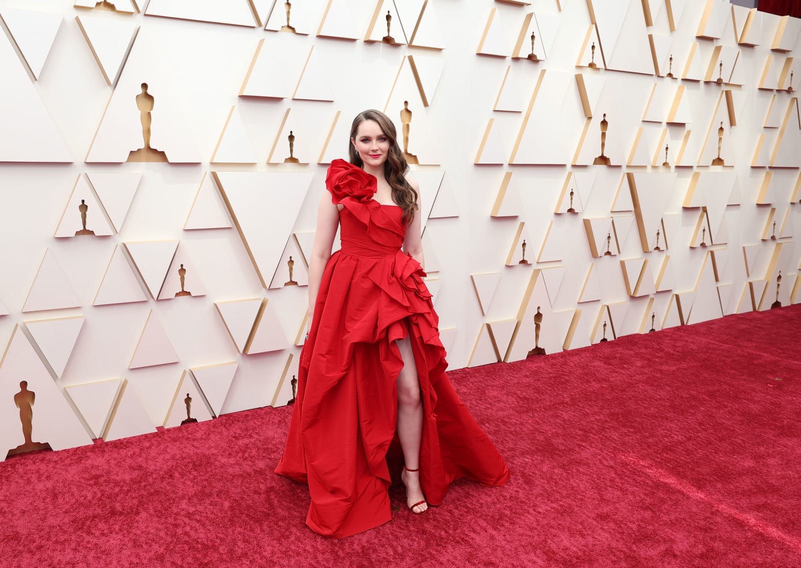 "CODA" actress Amy Forsyth in a one-shoulder red Marchesa gown with thigh-high cut. 