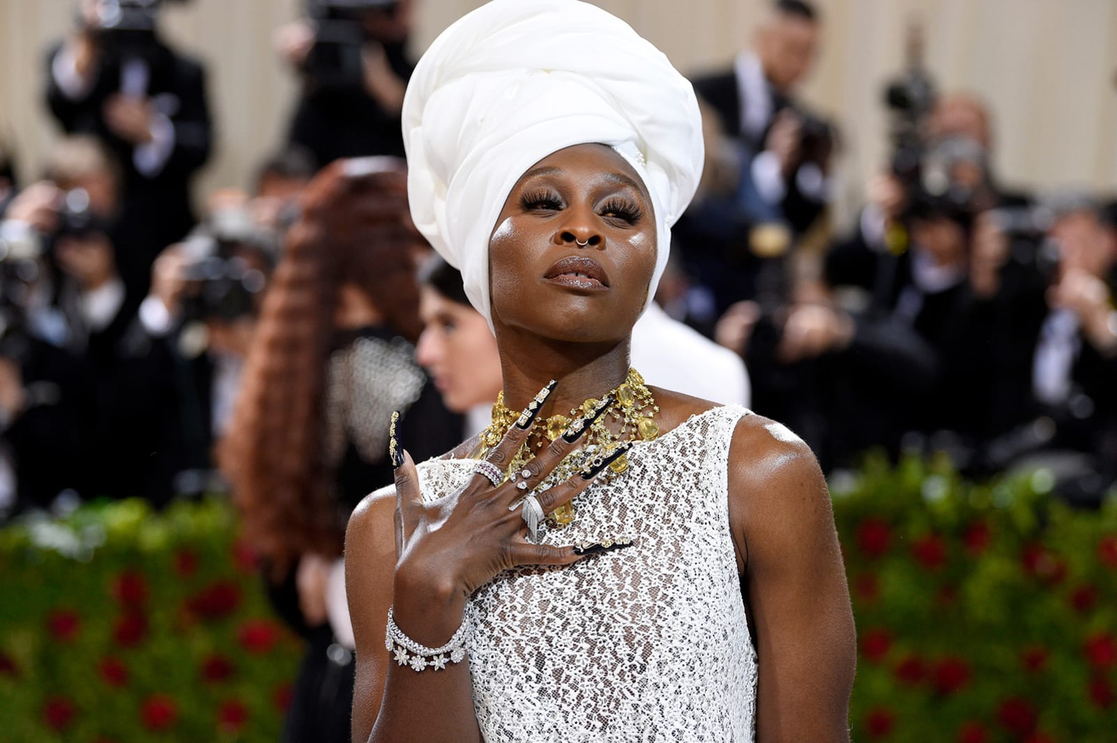 Cynthia Erivo swept down the red carpet in a white lace Louis Vuitton gown with a ruffled skirt, alongside a white headwrap and a golden necklace.