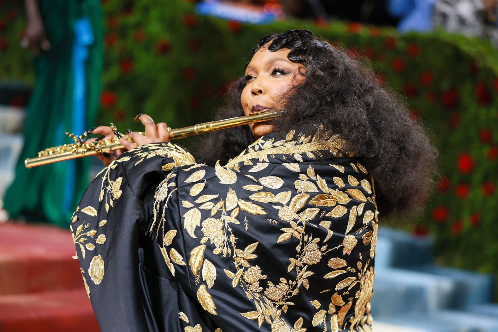 Lizzo stepped out in a black Thom Browne corset dress and a trailing gilded coat, and played a golden flute. 
