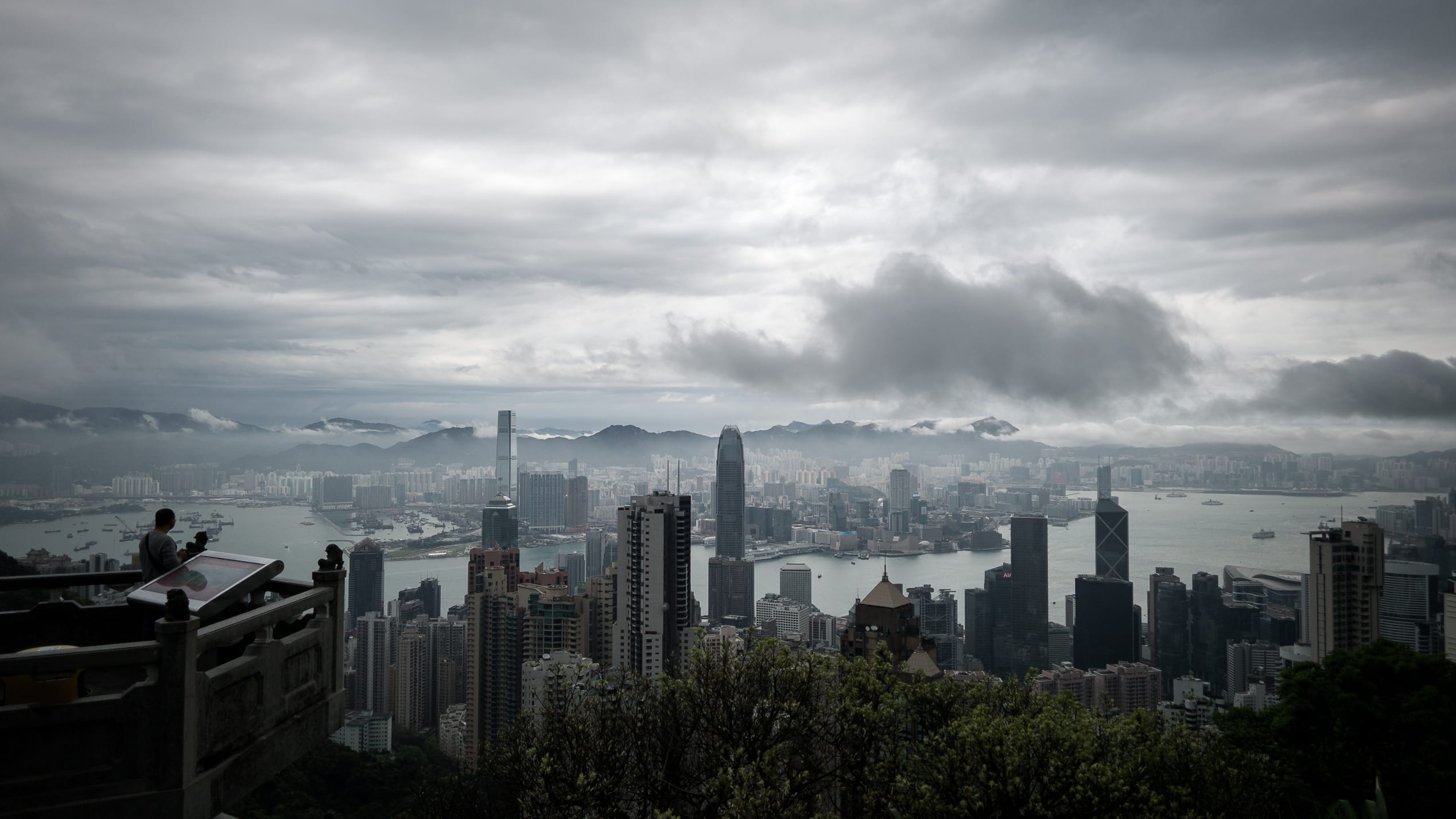 2014年4月2日，一名男子（L）在風暴來臨時看著這座城市的天際線。由于中國南方鄰近廣東省沿海地區(qū)的低壓低谷，暴風雨正在影響該市。