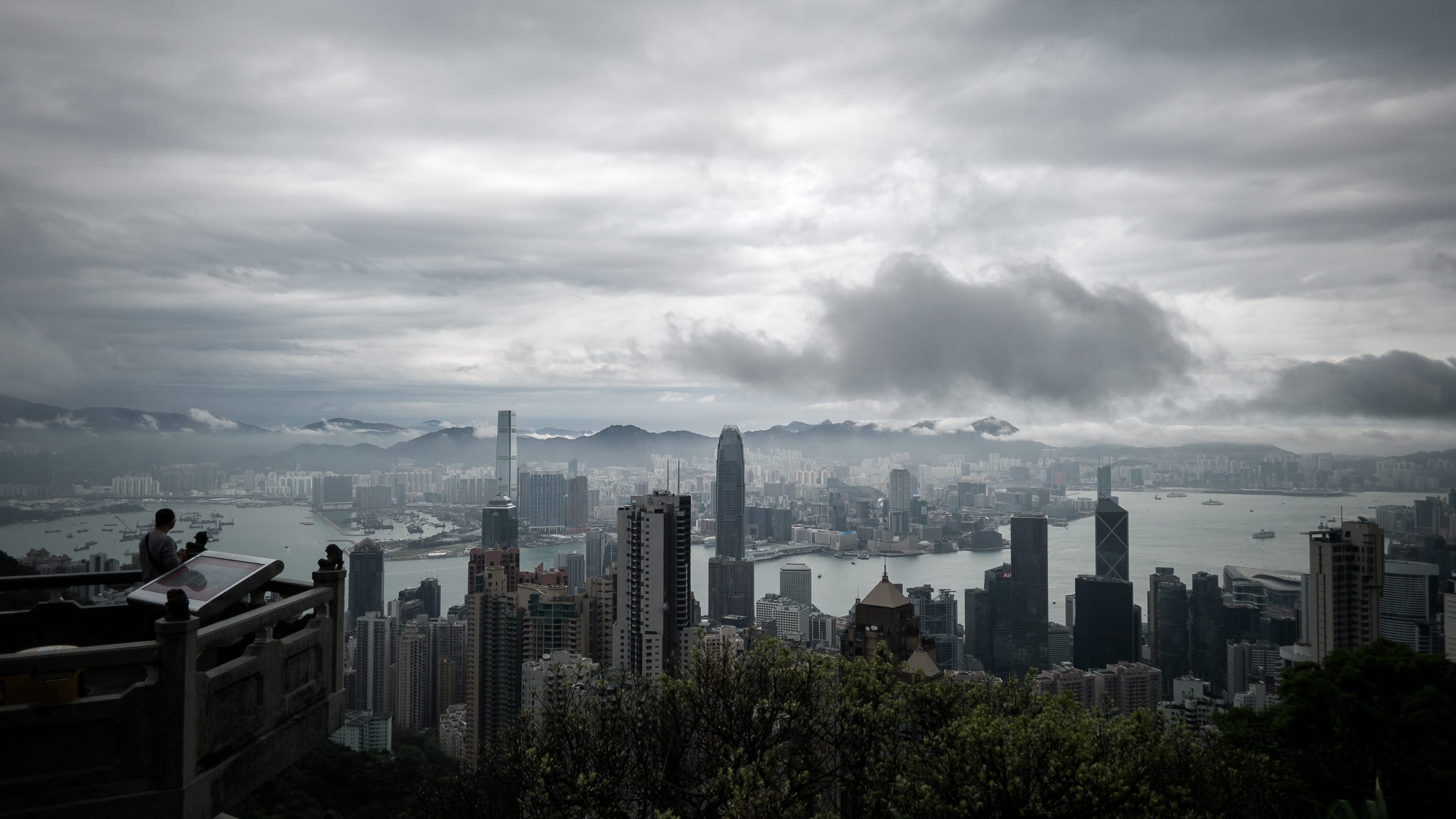 2014年4月2日，一名男子（L）在风暴来临时看着这座城市的天际线。由于中国南方邻近广东省沿海地区的低压低谷，暴风雨正在影响该市。