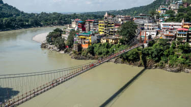 This photo taken on October 2, 2019 shows people walking on the Lakshman Jhula footbridge over the Ganges river in Rishikesh. - A French woman has been arrested for making a video of herself naked on a holy bridge in the Indian city of Rishikesh, police said on August 29. The 27-year-old now faces charges under India's internet law with a maximum sentence of three years jail if found guilty. (Photo by Laurène Becquart / AFP) (Photo by LAURENE BECQUART/AFP via Getty Images)
