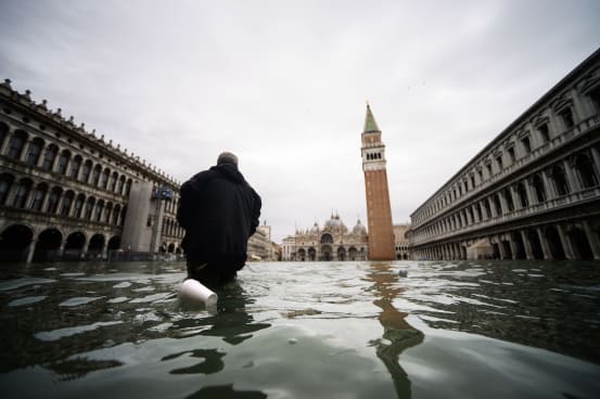 A man walks across the flooded St. Mark's Square on November 15, 2019. Credit: FILIPPO MONTEFORTE via Getty Images