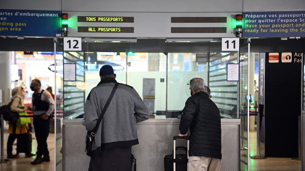 Travellers shows their documents to a border police officer at the immigration desk of Roissy Charles-de-Gaulle international airport, on February 1, 2021.