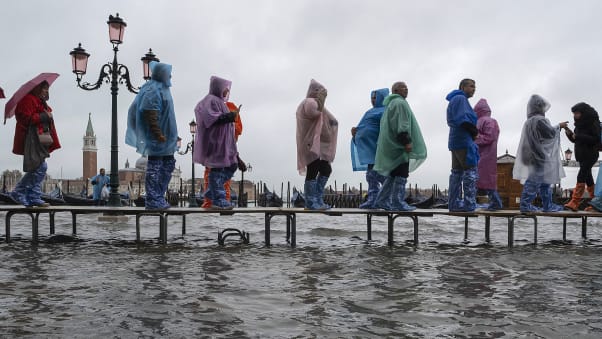 Tourists typically navigate Venice flooding on raised walkways.