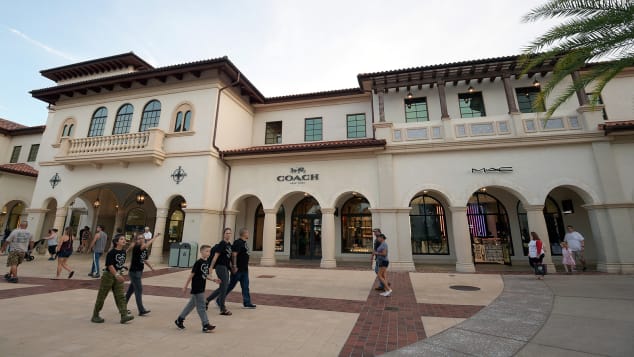 Before the coronavirus pandemic, visitors walk past Coach and MAC stores at Disney Springs in October 2019. 