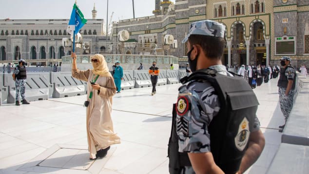 Security personnel standby as pilgrims arrive keeping social distancing to limit exposure and the potential transmission of the coronavirus.