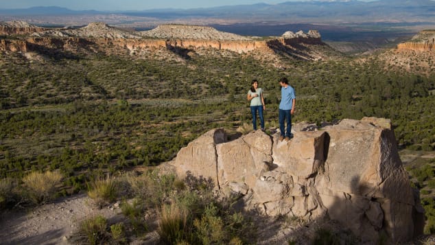 Two hikers stand in a mountain valley in Los Alamos County, New Mexico.