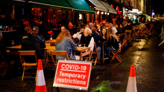 People drink outside at a cafe in Soho, in central London on September 23.