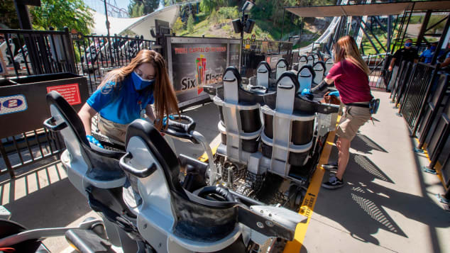 Employees sanitize roller coaster seats at Six Flags Magic Mountain in Valencia, California, on April 2 -- the second day that the park reopened after more than a year of being closed because of the pandemic. 