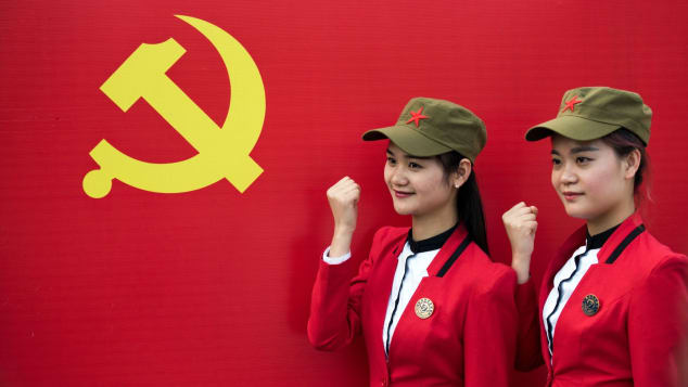 Tourists pose in front a flag of the Communist Party in Shaoshan, in central China's Hunan province in 2016. 