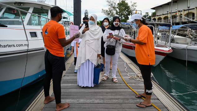 Passengers scan an app to monitor their health status before boarding a yacht in Langkawi, Malaysia, on September 17.
