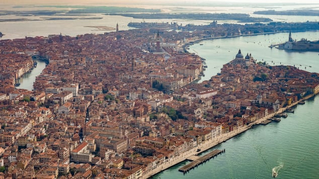 Nga ajri, ju mund të shihni rrjetin e kanaleve të Venecias që shkëlqejnë në rrezet e diellit.