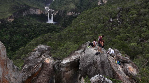 Pengunjung beristirahat di formasi batuan di dekat air terjun Saltos do Rio Preto di Chapada dos Veadeiros.