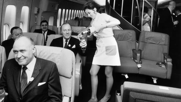 A Pan Am flight attendant serves champagne in the first class cabin of a Boeing 747 jet. 