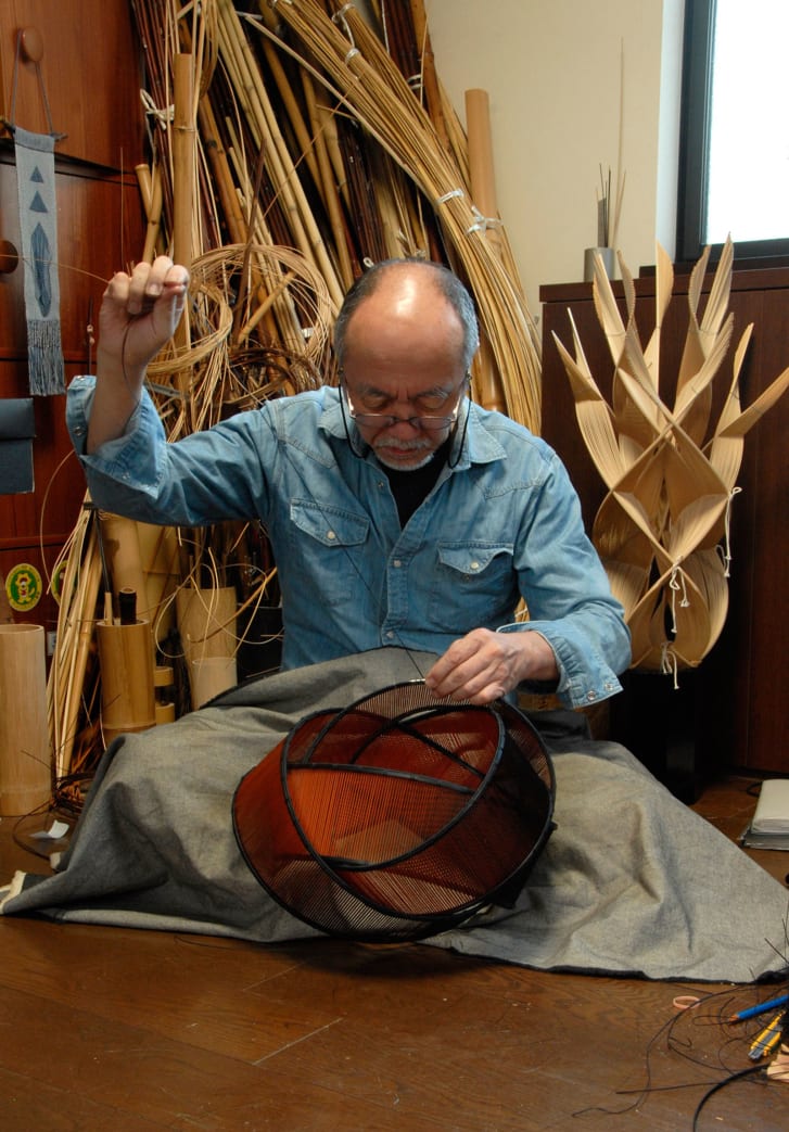 Japanese artist Fujitsuka Shosei works on a bamboo basket in his studio.