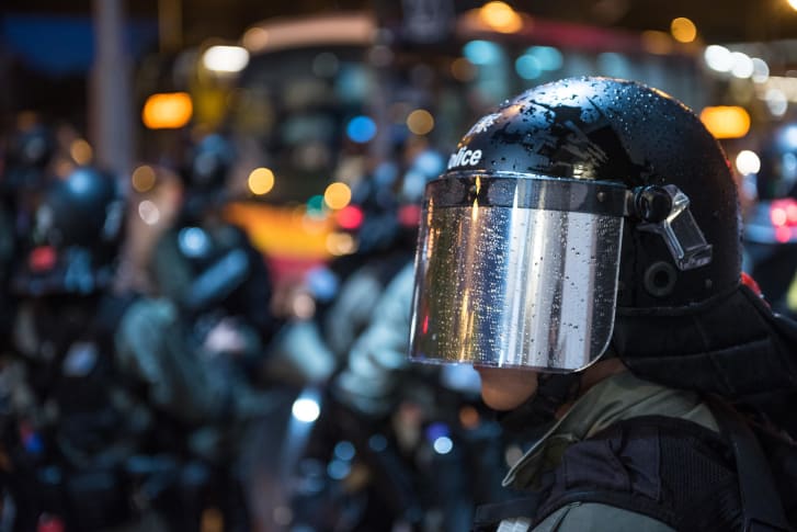 A policeman wears metallic gray material in his helmet as he stands on guard in the rain during a peaceful demonstration in Hong Kong.