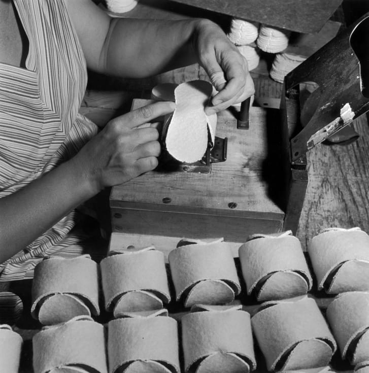 The wool cover is being applied to the cemented halves of a tennis ball. 