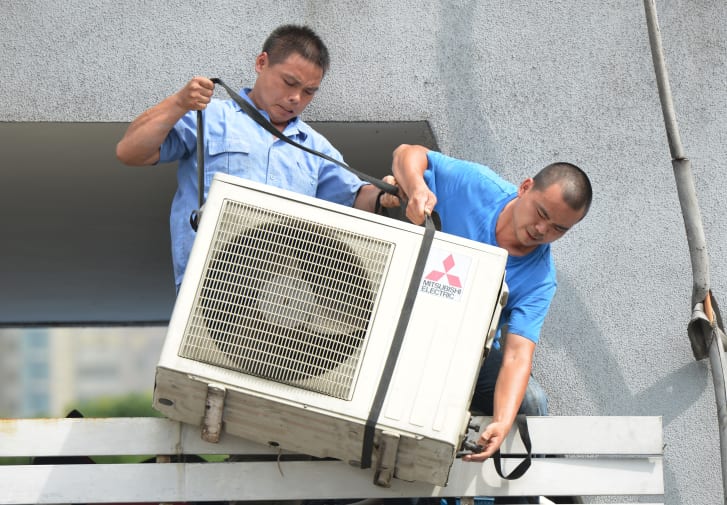 Workers install an airconditioning unit in a food stall in Shanghai.