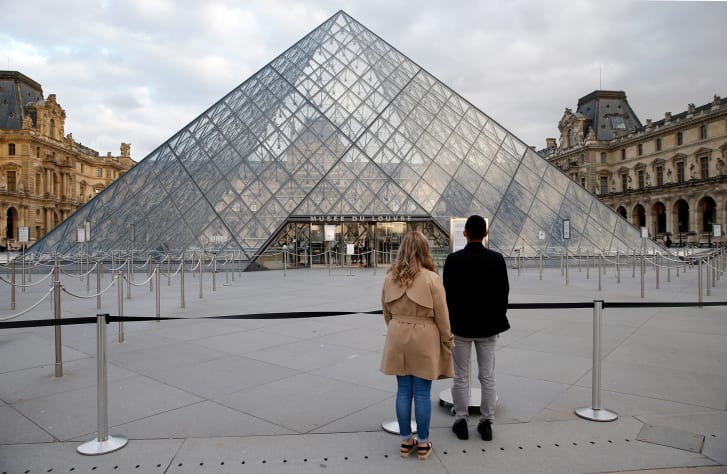 Tourists read a sign informing of the closing of the Louvre museum on March 13, 2020 in Paris, France.