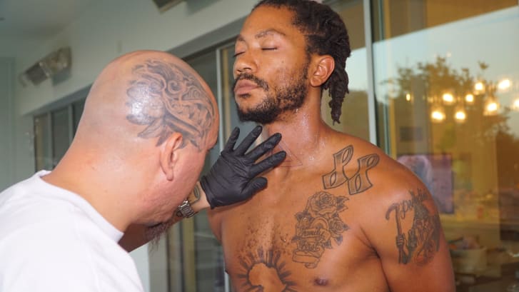 Guijosa prepares to tattoo Derrick Rose's neck.
