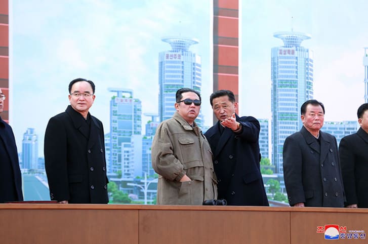 Kim Jong Un pictured in front of an artistic rendering of the new development.