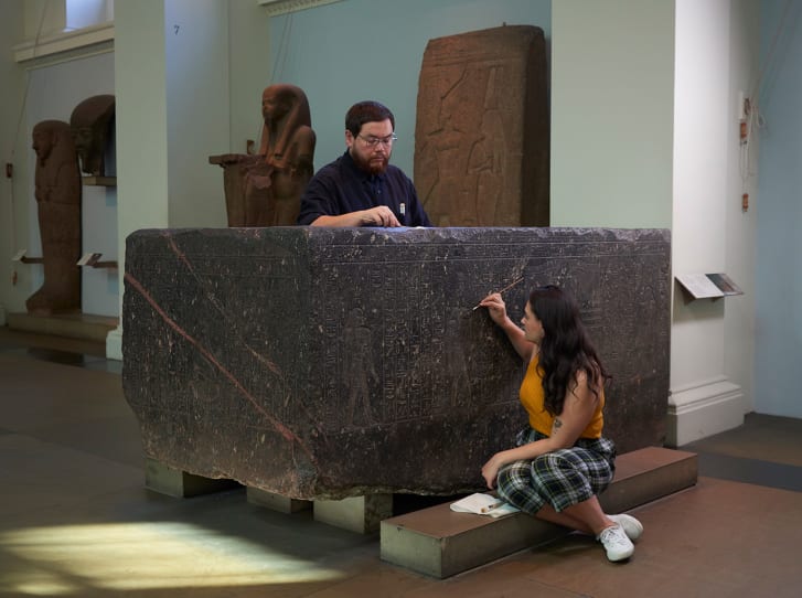 Senior Conservator Stephanie Vasiliou and former conservation student Shoun Obana clean "The Enchanted Basin," sarcophagus of Hapmen, 600 BC, on display at The British Museum.