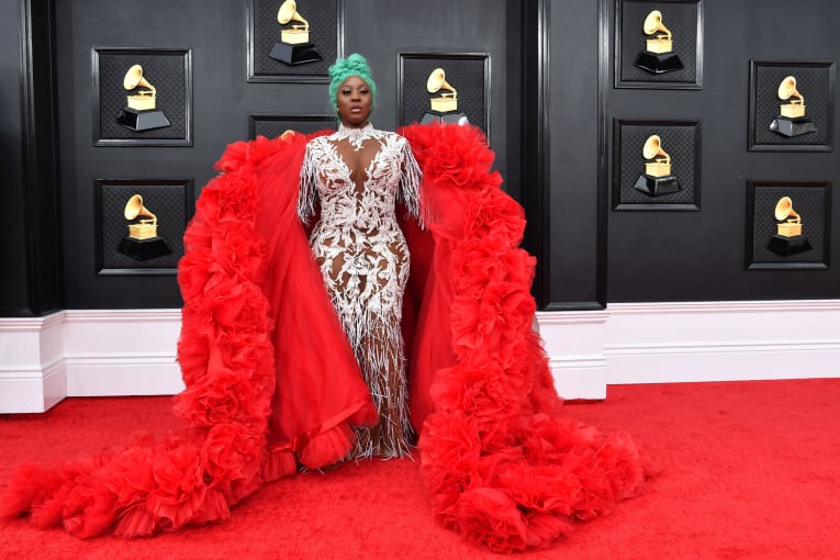 La artista de dancehall Spice llegó con una voluminosa túnica roja que dejó caer al suelo mientras posaba para los fotógrafos.