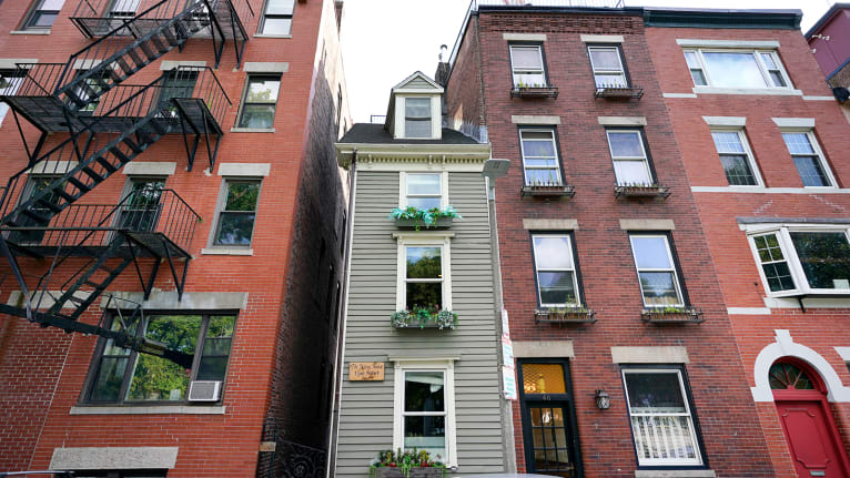 Boston's famous Skinny House, middle, is seen, Friday, Aug. 13, 2021, and is on the market for $1.2 million. This is the first time the vertically rectangular-shaped house has been on the market since 2017 when it was sold for $900,000. The home, located in Boston's North End, is about 1,165 square feet and is barely 10 feet wide at its widest point. (AP Photo/Elise Amendola)