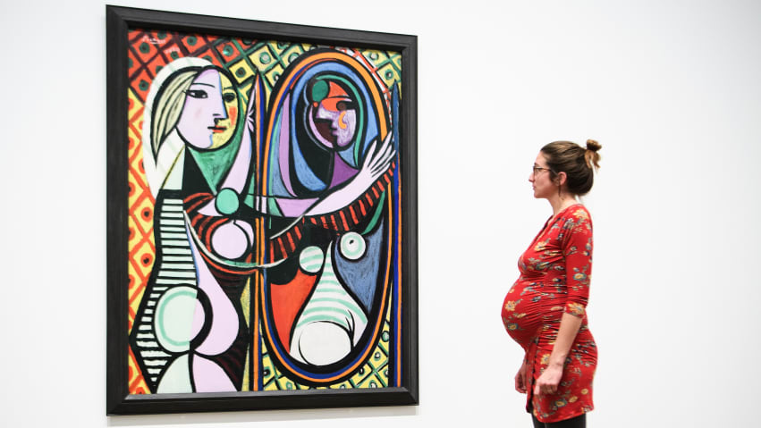A pregnant woman studies "Girl Before a Mirror" on March 6, 2018, during an exhibition at the Tate Modern in London.