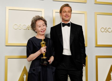 Yuh-jung Youn holds her best supporting actress Oscar as she stands next to presenter Brad Pitt in the press room. Chris Pizzello/Pool/Getty Images